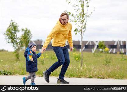 family, childhood, fatherhood, leisure and people concept - happy father and little son with pinwheel toy walking outdoors