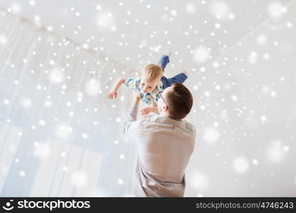 family, childhood, fatherhood, leisure and people concept - happy father and little son playing and having fun at home over snow