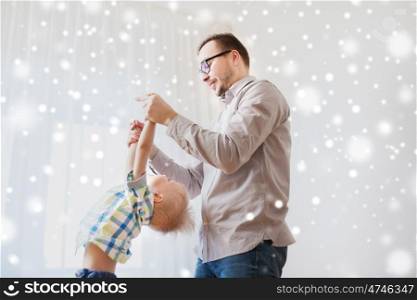 family, childhood, fatherhood, leisure and people concept - happy father and little son playing and having fun at home over snow