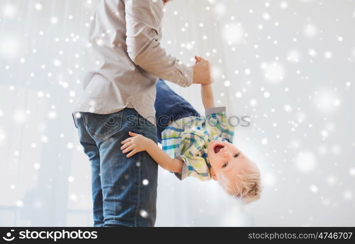 family, childhood, fatherhood, leisure and people concept - happy father and little son playing and having fun at home over snow