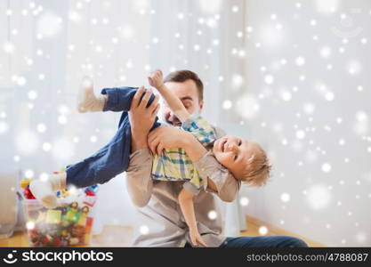 family, childhood, fatherhood, leisure and people concept - happy father and little son playing and having fun at home over snow