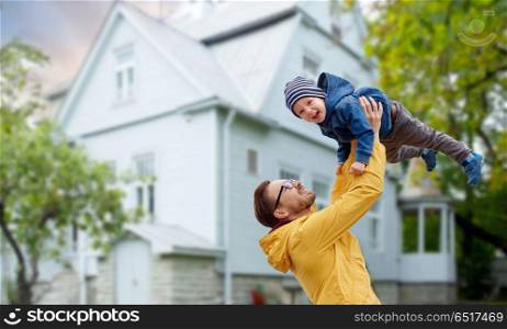 family, childhood, fatherhood, leisure and people concept - happy father and little son playing and having fun outdoors over house background. father with son playing and having fun outdoors. father with son playing and having fun outdoors
