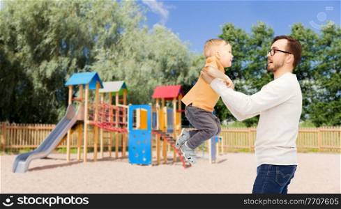 family, childhood, fatherhood, leisure and people concept - happy father and little son playing and having fun over children&rsquo;s playground background. father with son playing and having fun
