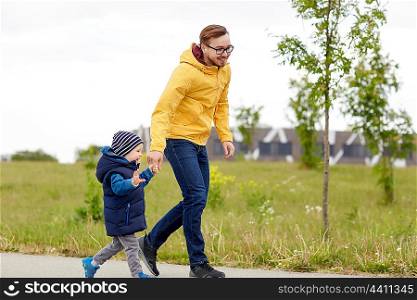 family, childhood, fatherhood, leisure and people concept - happy father and little son walking outdoors