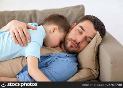 family, childhood, fatherhood, leisure and people concept - portrait of happy father and little son sleeping on sofa at home. happy father and son sleeping on sofa at home