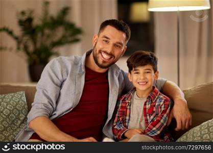 family, childhood, fatherhood, leisure and people concept - portrait of happy smiling father and little son hugging at home in evening. portrait of happy father and little son at home