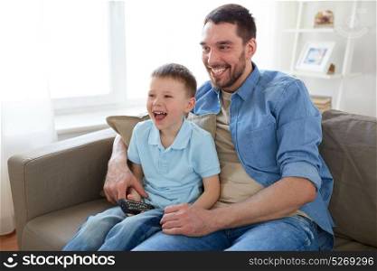 family, childhood, fatherhood, technology and people concept - happy father and little son with remote control watching tv at home. father and son with remote watching tv at home