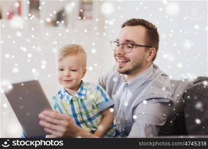family, childhood, fatherhood, technology and people concept - happy father and son with tablet pc computer playing at home over snow