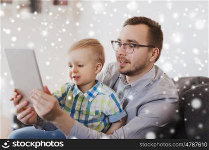 family, childhood, fatherhood, technology and people concept - happy father and son with tablet pc computer playing at home over snow