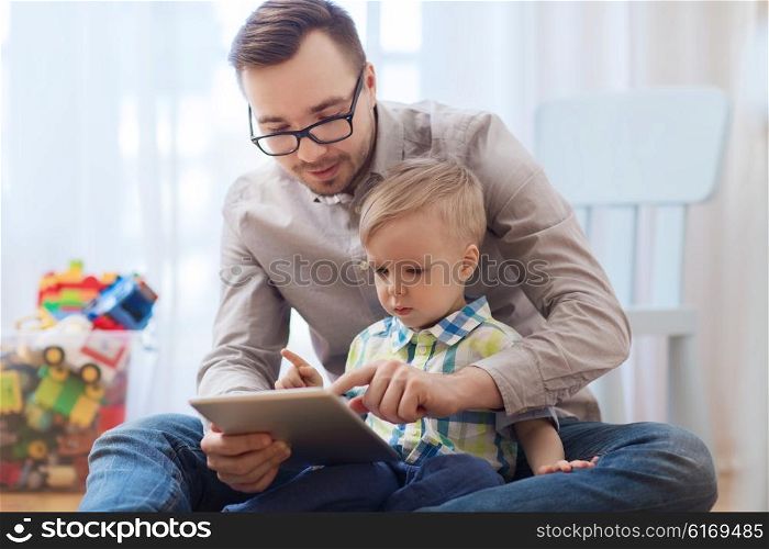 family, childhood, fatherhood, technology and people concept - happy father and son with tablet pc computer playing at home
