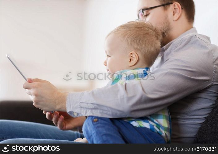 family, childhood, fatherhood, technology and people concept - happy father and son with tablet pc computer playing at home