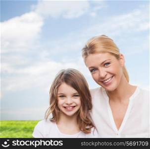 family, childhood, happiness and people - smiling mother and little girl over blue sky and grass background