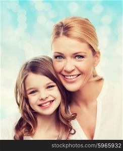 family, childhood, happiness and people - smiling mother and little girl over blue lights background