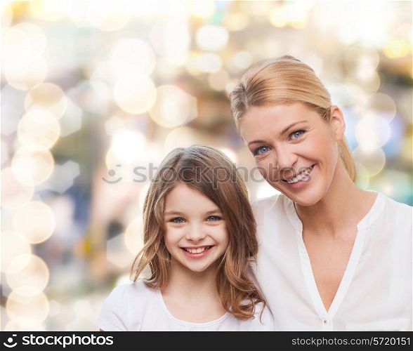 family, childhood, happiness and people - smiling mother and little girl over lights background