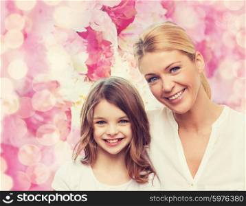 family, childhood, happiness and people - smiling mother and little girl over pink lights background