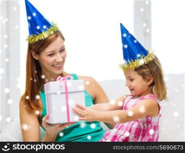 family, childhood, holidays and people concept - happy mother and daughter in blue party hats with gift box