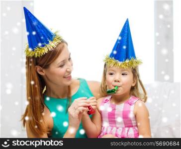 family, childhood, holidays and people concept - happy mother and daughter in blue party hats with party horns