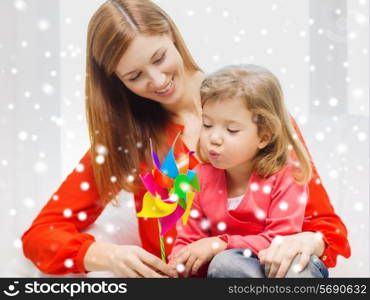 family, childhood, holidays and people concept - happy mother and daughter with pinwheel toy