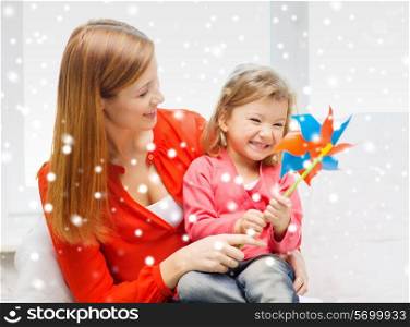 family, childhood, holidays and people concept - happy mother and daughter with pinwheel toy