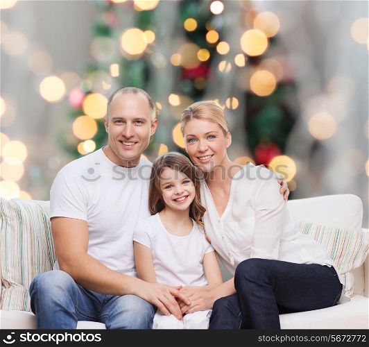 family, childhood, holidays and people concept - smiling mother, father and little girl over christmas tree lights background
