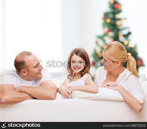 family, childhood, holidays and people - smiling mother, father and little girl over living room and christmas tree background