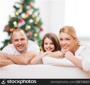 family, childhood, holidays and people - smiling mother, father and little girl over living room and christmas tree background
