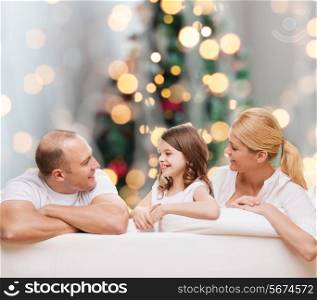family, childhood, holidays and people - smiling mother, father and little girl over christmas tree lights background