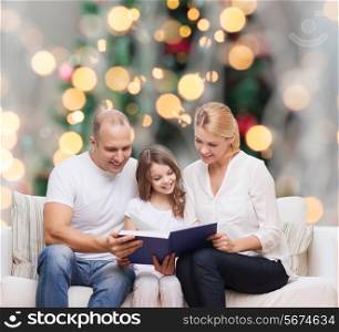 family, childhood, holidays and people - smiling mother, father and little girl reading book over living room and christmas tree background