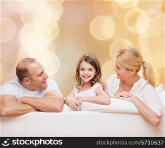 family, childhood, holidays and people - smiling mother, father and little girl over beige lights background