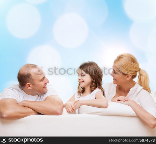 family, childhood, holidays and people - smiling mother, father and little girl over blue lights background