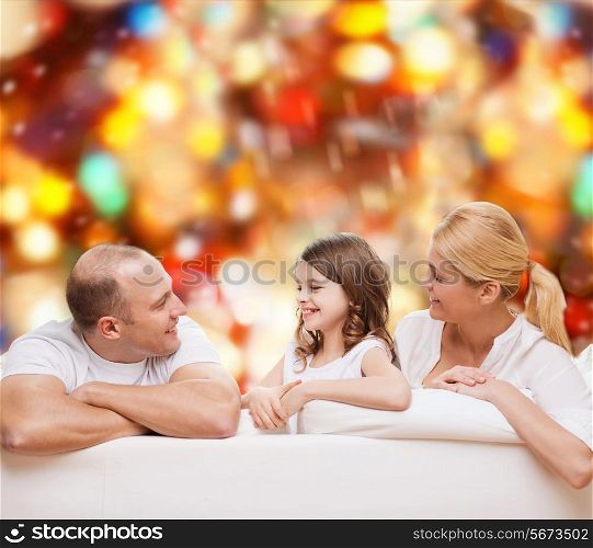 family, childhood, holidays and people - smiling mother, father and little girl over red lights background