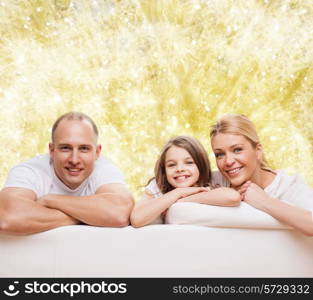 family, childhood, holidays and people - smiling mother, father and little girl over yellow lights background