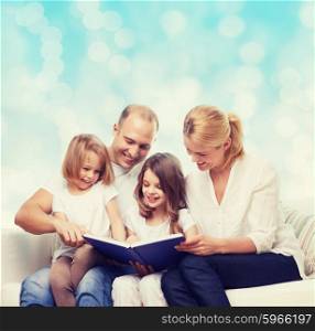 family, childhood, holidays and people - smiling mother, father and little girls reading book over blue lights background