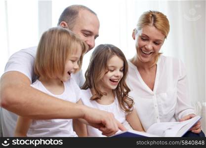 family, childhood, holidays and people - smiling mother, father and little girls reading book at home