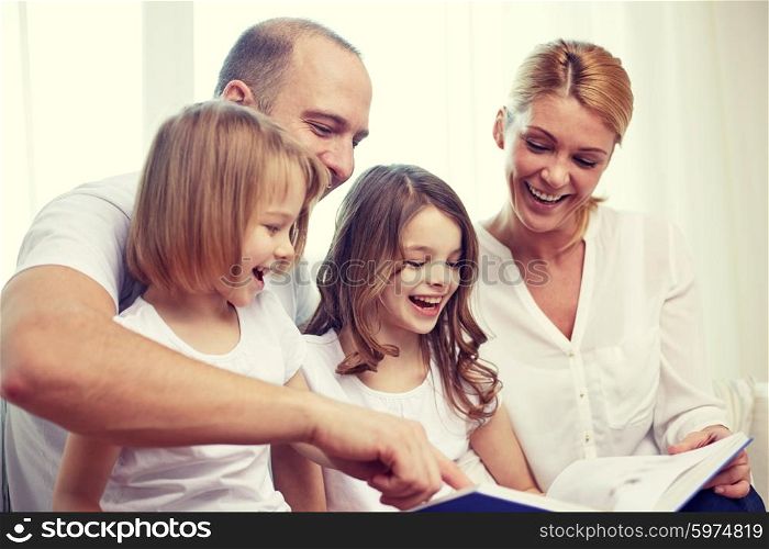 family, childhood, holidays and people - smiling mother, father and little girls reading book at home