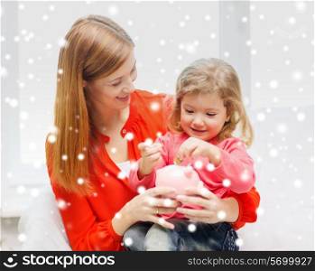 family, childhood, holidays, finances and people concept - happy mother and daughter with piggy bank
