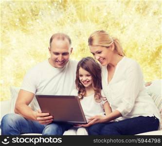 family, childhood, holidays, technology and people concept - smiling family with laptop computer over golden lights background