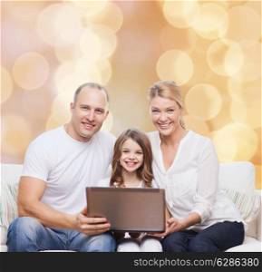 family, childhood, holidays, technology and people concept - smiling family with laptop computer over beige lights background