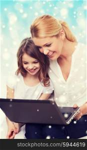 family, childhood, holidays, technology and people concept - smiling mother and little girl with laptop computer over blue background with snow