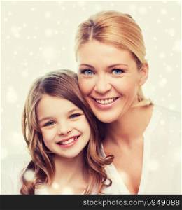 family, childhood, motherhood, people and happiness concept - smiling mother and little girl over snowflakes background