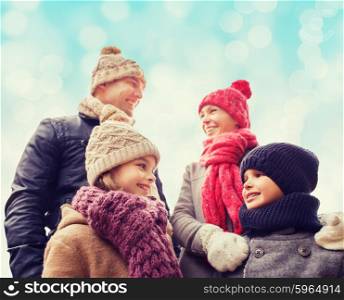 family, childhood, season and people concept - happy family in winter clothes over blue lights background