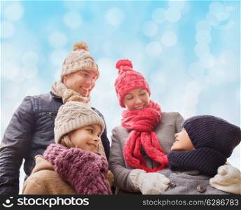 family, childhood, season and people concept - happy family in winter clothes over blue lights background