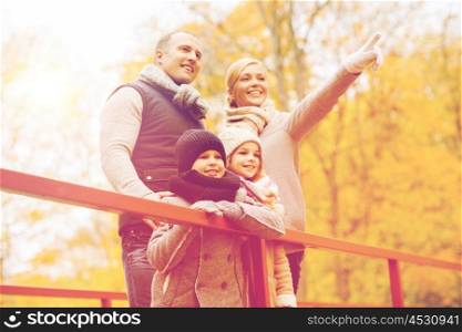family, childhood, season and people concept - happy family pointing finger in autumn park