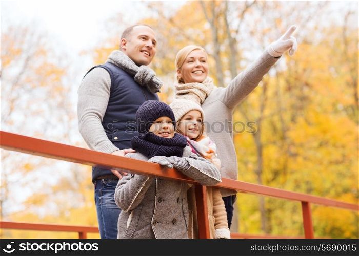 family, childhood, season and people concept - happy family pointing finger in autumn park