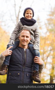 family, childhood, season and people concept - happy father and son having fun in autumn park