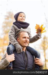 family, childhood, season and people concept - happy father and son having fun in autumn park