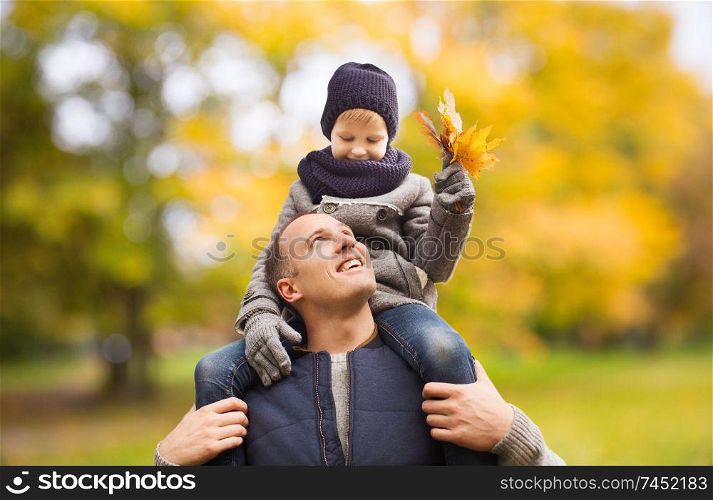 family, childhood, season and people concept - happy father and son having fun in autumn park. happy family having fun in autumn park