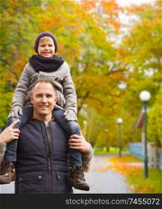 family, childhood, season and people concept - happy father and son having fun in autumn park. happy family having fun in autumn park