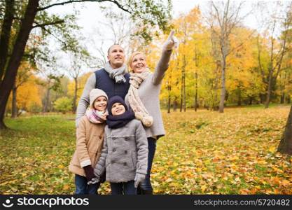family, childhood, season, gesture and people concept - happy family pointing finger in autumn park