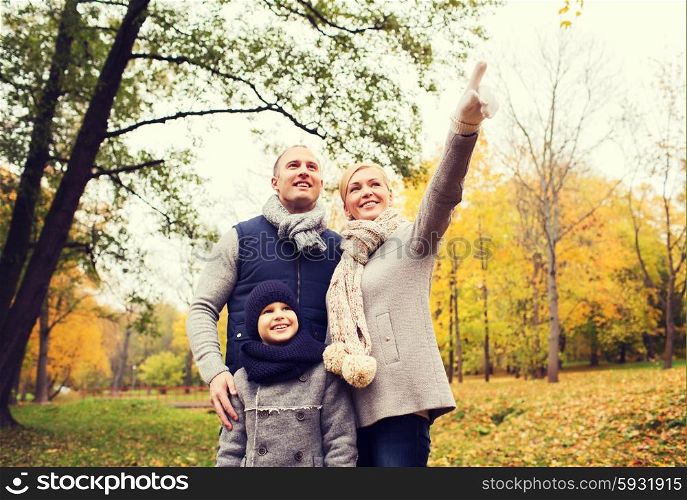 family, childhood, season, gesture and people concept - happy family pointing finger in autumn park